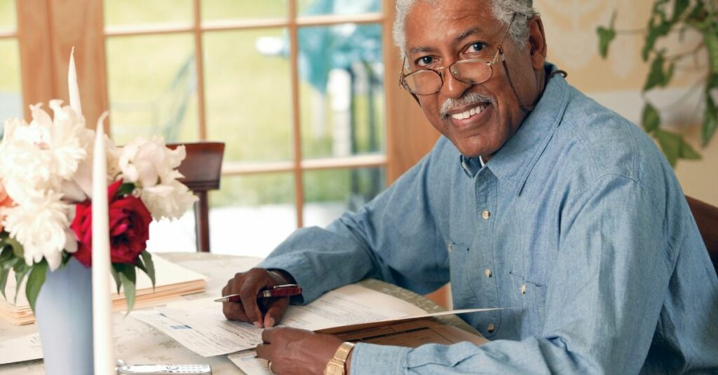 african american senior man at kitchen table smiling into camera